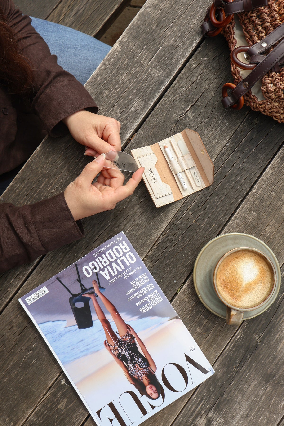Woman using a manicure kit at at table with a coffee and Vogue magazine
