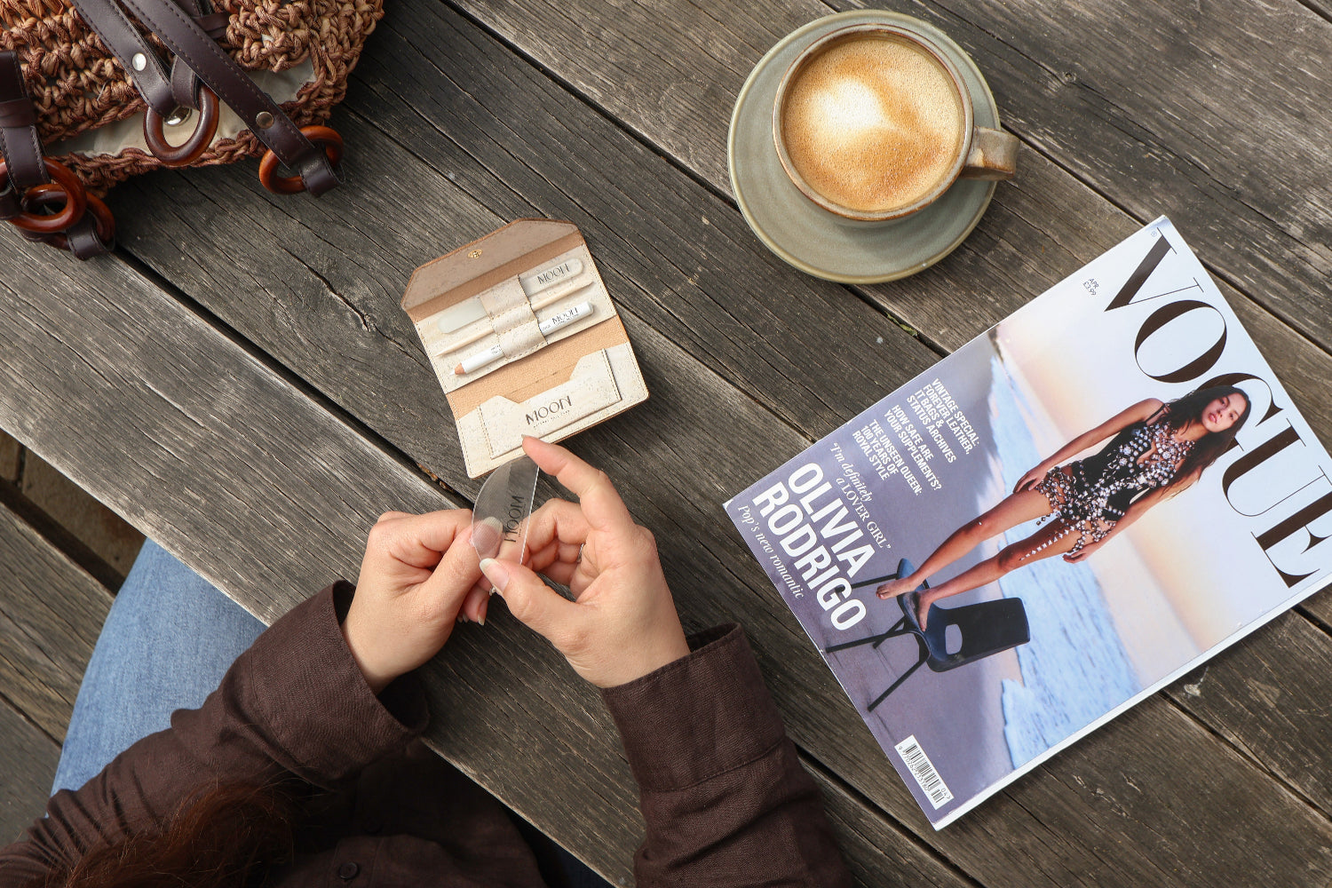 Woman using a manicure kit at at table with a coffee and Vogue magazine
